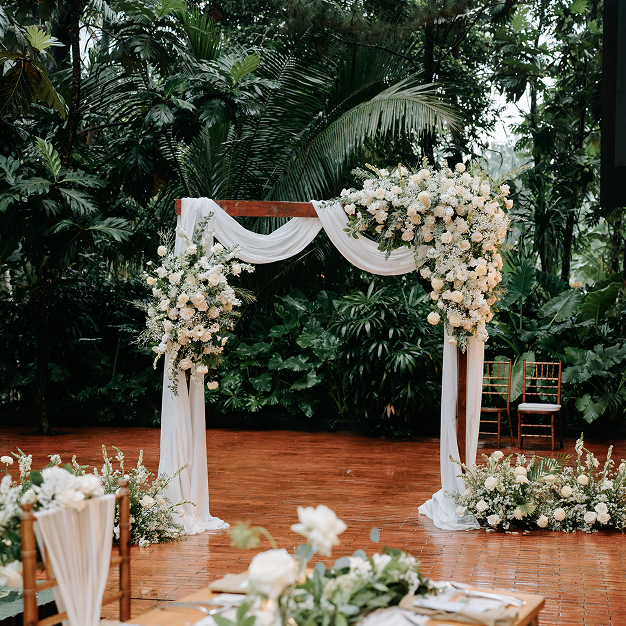 Elegant white floral wedding arch and architectural wooden altar in an outdoor garden