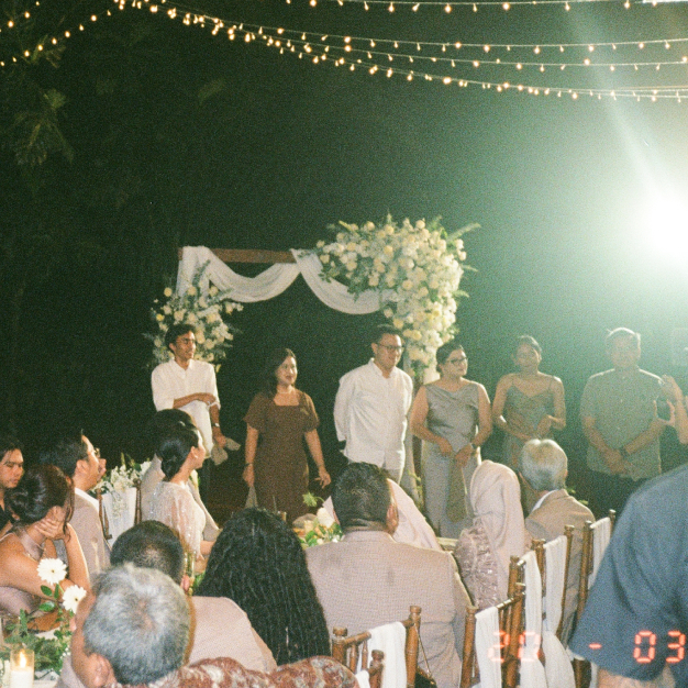 Candid film-style shot of a wedding ceremony at Titik Dua Ubud under fairy lights at night