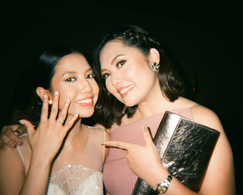 A bride showing her wedding ring to a bridesmaid during a night celebration in Ubud