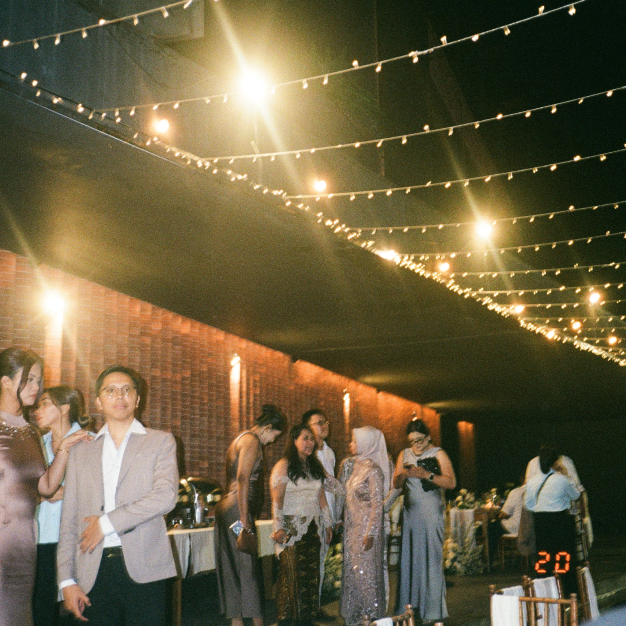 Guests mingling along an architectural red brick wall at Titik Dua wedding after-party